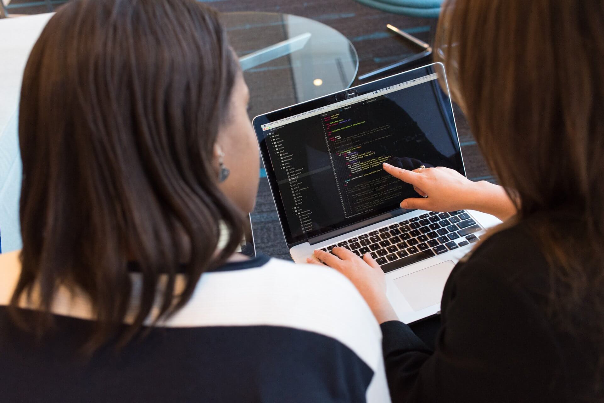 Two women looking at the code on a laptop